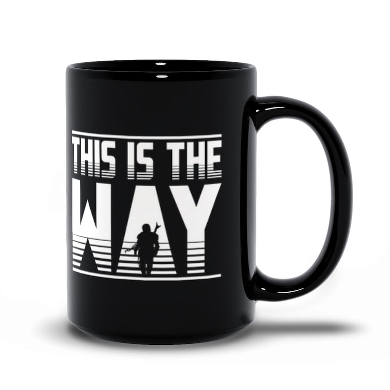 Puede incluir: Taza de caf&eacute; de cer&aacute;mica negra con un gr&aacute;fico blanco que dice "This is the Way" con una silueta de una persona sosteniendo un arma frente a un fondo a rayas.