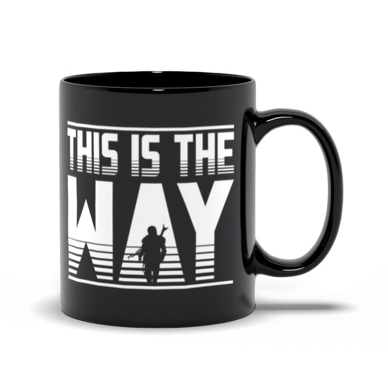 Puede incluir: Taza de caf&eacute; de cer&aacute;mica negra con un gr&aacute;fico blanco de una figura subiendo escaleras con el texto "This is the Way".