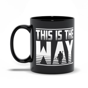 Puede incluir: Taza de caf&eacute; de cer&aacute;mica negra con un gr&aacute;fico blanco de una figura con una capucha y el texto "This is the Way".