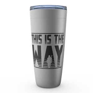 Puede incluir: Una taza de viaje plateada con un gr&aacute;fico negro que dice "This is the Way" con una silueta de un personaje mandaloriano.