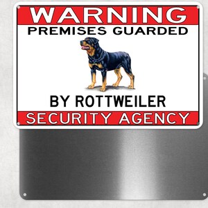 May include: A rectangular metal sign with a red and white border. The sign reads "WARNING PREMISES GUARDED BY ROTTWEILER SECURITY AGENCY." A detailed illustration of a Rottweiler dog is in the center of the sign.