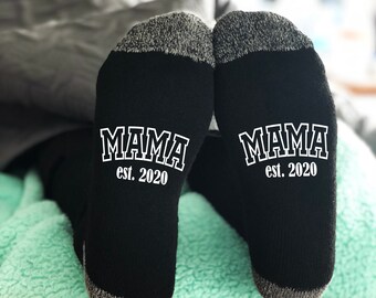 May include: A pair of black socks with white text that reads "MAMA est. 2020" on each sock.