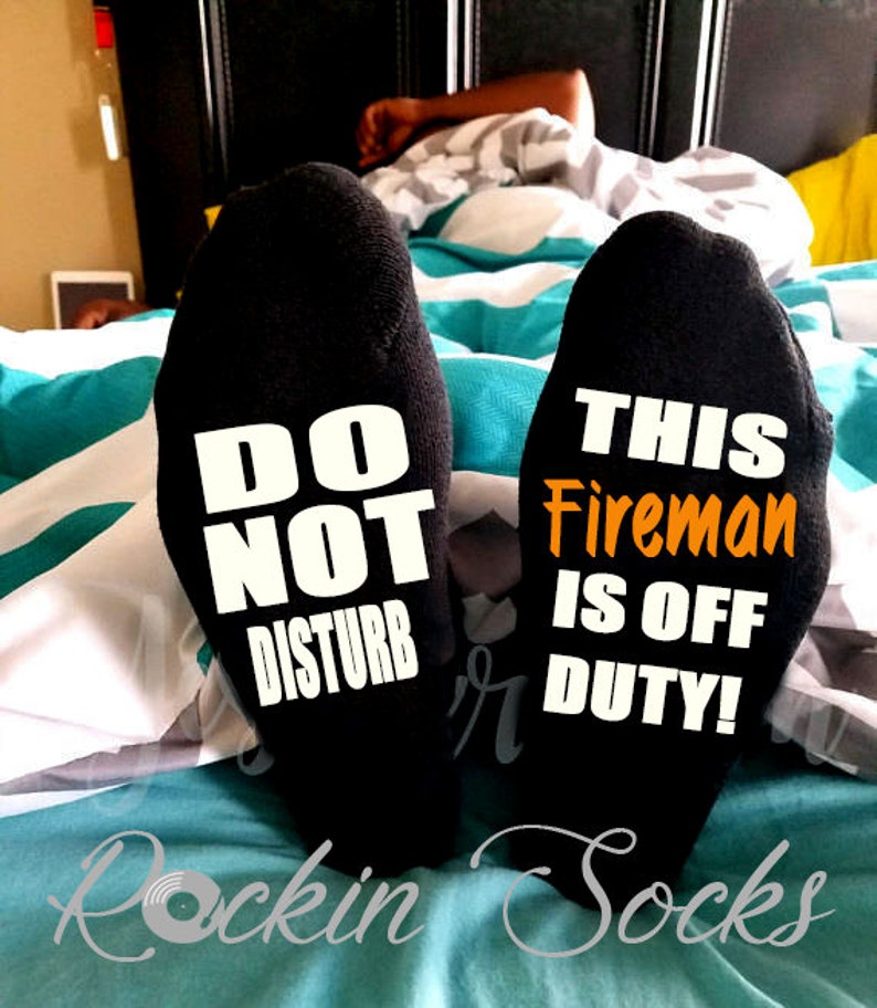 May include: A pair of black socks with white text. One sock says "Do Not Disturb" and the other says "This Fireman Is Off Duty!"