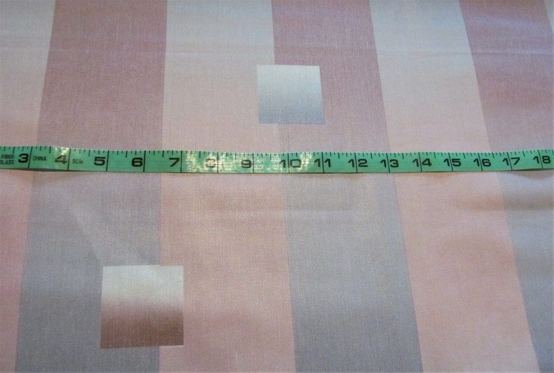May include: A close-up of a pink and white striped fabric with a measuring tape across the middle. The tape reads 3 to 18 inches.