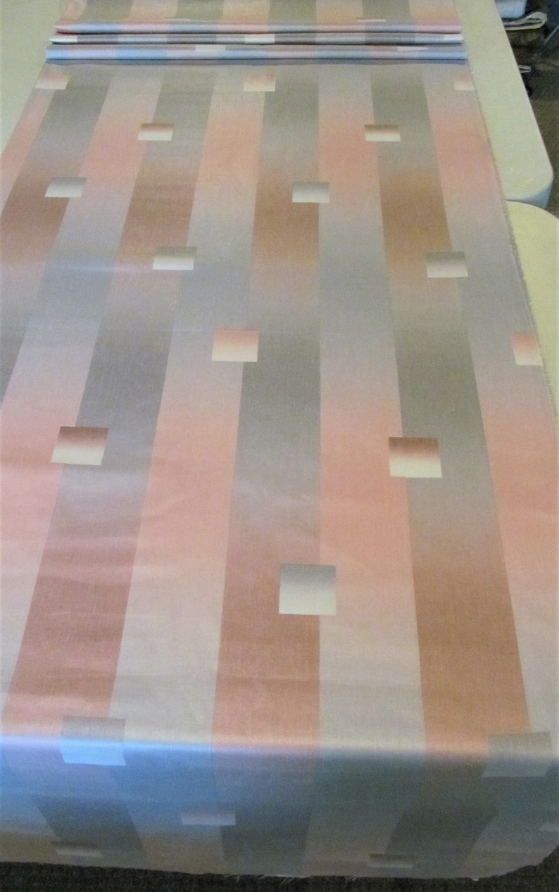May include: A fabric with a striped pattern in shades of pink, gray, and white. The fabric has a subtle sheen and features a repeating pattern of squares.