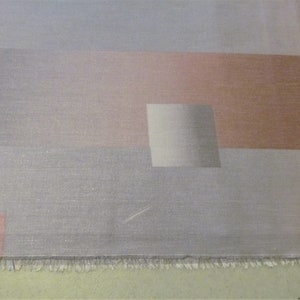 May include: A close-up of a fabric with a geometric pattern in shades of gray, pink, and brown. The fabric has a subtle shimmer and a textured surface.