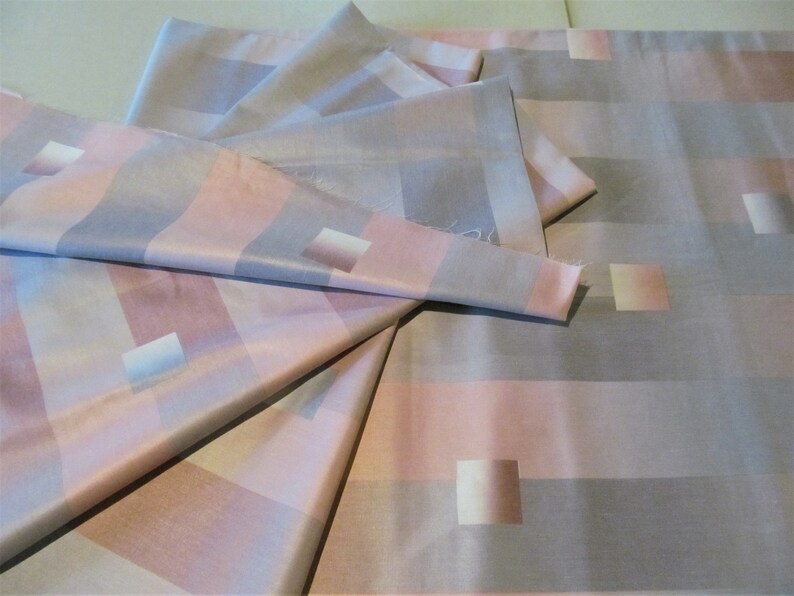 May include: A stack of fabric in a pink and gray plaid pattern. The fabric is soft and silky, and it would be perfect for making a dress, skirt, or blouse.