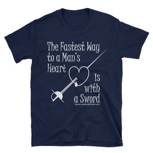 May include: Navy blue t-shirt featuring white text and a graphic of a heart pierced by a sword. The text reads "The Fastest Way to a Man's Heart is with a Sword" with the website cavalierattitude.com.