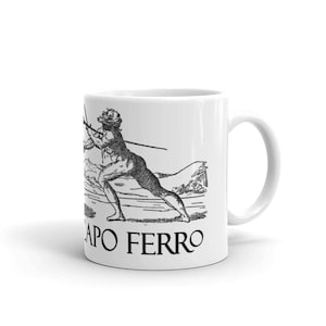 May include: White ceramic mug with a black and white illustration of a person holding a spear. The text "CAPO FERRO" is printed on the mug.