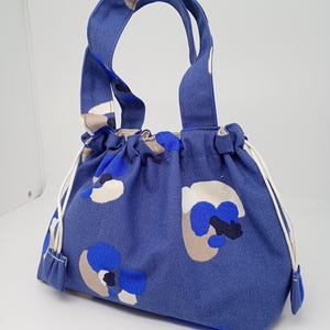 Petit sac à poignées, en tissu résistant fond bleu jean avec motifs blanc noir beige, doublé en coton beige.