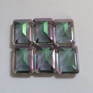 Pode incluir: Seis gemas quadradas de vidro verde e roxo iridescentes.