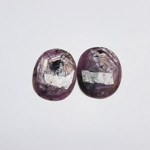 May include: Two oval-shaped gemstones with a purple hue and a star-like pattern in shades of black, white, and silver.