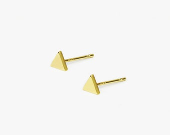 May include: A pair of gold triangle stud earrings. The earrings are small and simple, making them a versatile accessory for any occasion.