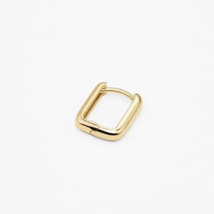 May include: Gold square hoop earrings. The earrings are made of a thick, solid metal and have a simple, modern design.