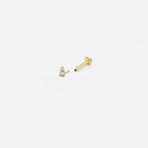 May include: A gold nose stud with two small clear gemstones set in a triangle shape.