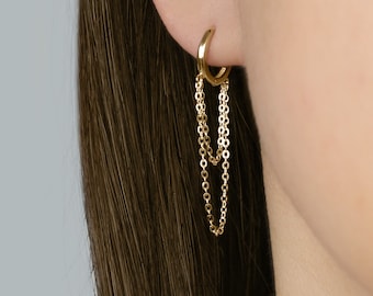May include: Gold hoop earrings with two dangling chains. The chains are made of small, linked circles.