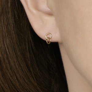 May include: Gold double circle earrings. The earrings are made of two interlocking circles.