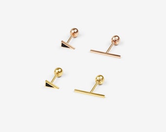 May include: Set of four gold and rose gold stud earrings with black enamel accents. Two earrings feature a triangle shape and two earrings feature a bar shape.