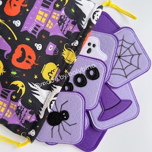 Op de afbeelding: Een Halloween-thema trekkoordtas met een zwarte achtergrond en paarse, oranje en gele illustraties. De tas staat naast verschillende paarse vilten onderzetters met Halloween-ontwerpen.