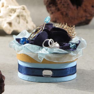decoratieve ovale kartonnen doos, marineblauwe en lichtblauwe tinten, met stof en bloemen versierd met enkele parels