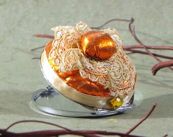 Pocket mirror with orange fabric, cream Ribbon and lace.