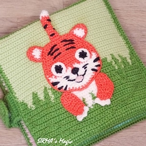 May include: A green crocheted baby book with a cute orange and white tiger applique. The book has a flap on the side and the text "SIRMA's Magic" is visible on the bottom.