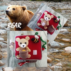 May include: A red and grey crocheted baby activity cube with a bear, bee, and other textures. The cube is labelled "BEAR".