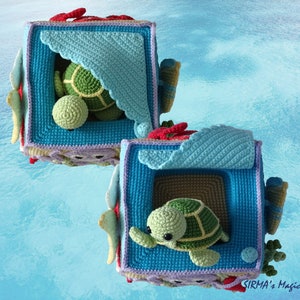 May include: Two crocheted boxes with a sea turtle design. The boxes are blue, green and purple with red accents. The boxes are open and each has a crocheted sea turtle inside.
