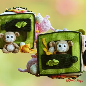 May include: A handmade crochet activity cube for babies, featuring a green and brown color scheme. The cube has various interactive elements, including a monkey, banana, and other animal figures. The design is soft and colorful, perfect for sensory play.