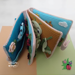 May include: A handmade crochet book with colorful pages featuring a butterfly, ladybugs, a caterpillar, and a sun. The book has a blue, pink, and brown color scheme, with the text "SIRMA's Magic" on the bottom left.