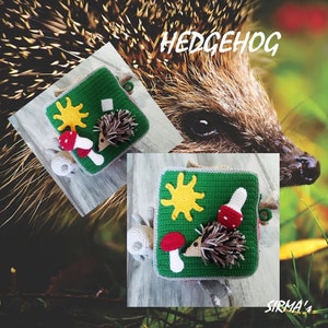 May include: A green and grey crocheted square with a hedgehog, mushroom, and sun design. The text "HEDGEHOG" is written in white letters on a brown background. The text "SIRMA's" is written in white letters on a brown background.