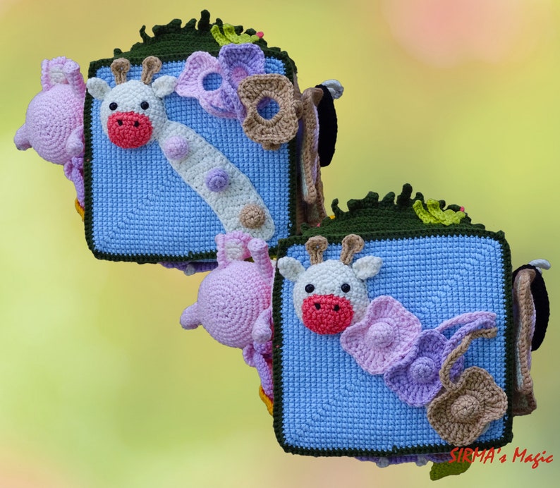 May include: Crocheted giraffe and other animal-themed decorations. The giraffe has a white face with a red mouth and is on a blue square. Other decorations include a pink elephant, flowers, and a brown purse.