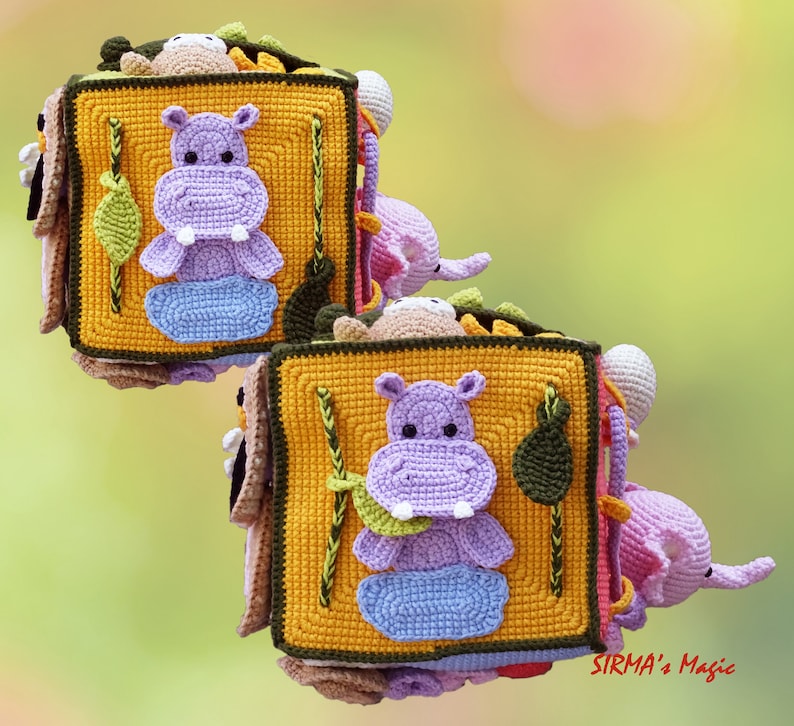 May include: Crocheted soft book featuring a purple hippo, blue water, and green leaf on a yellow square. The book has a brown border and includes other crocheted animals. The background is a soft green and yellow.