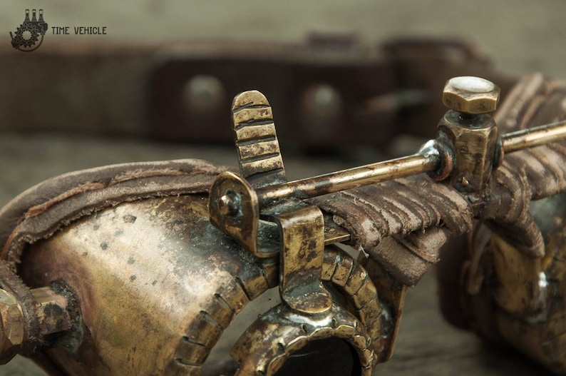 Op de afbeelding: Close-up van een steampunk-bril met een messing frame, leren banden en een messing hendel. De bril heeft een vintage uitstraling en is gemaakt met ingewikkelde details.