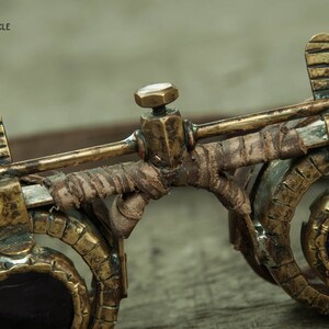 Op de afbeelding: Close-up van een steampunk-bril met messing en lederen accenten. De bril heeft ronde glazen en een leren band.