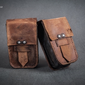 Puede incluir: Dos bolsas de cuero marrón con detalles metálicos y costuras. Las bolsas tienen cierre de solapa y están hechas de cuero envejecido.