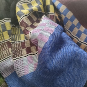 May include: A black, blue, yellow and purple woven scarf with a checkered pattern.