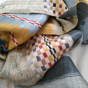 May include: A multi-coloured woven scarf with a checkered pattern in shades of blue, yellow, red and black.