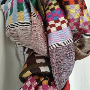 May include: A colourful woven scarf with a checkered pattern in shades of red, blue, green, pink and brown.