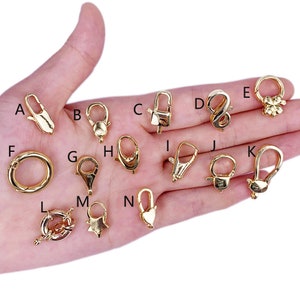 May include: Assortment of 14 gold-tone metal clasps and connectors for jewellery making. The clasps are in various shapes, including round, oval, heart, star, and infinity.