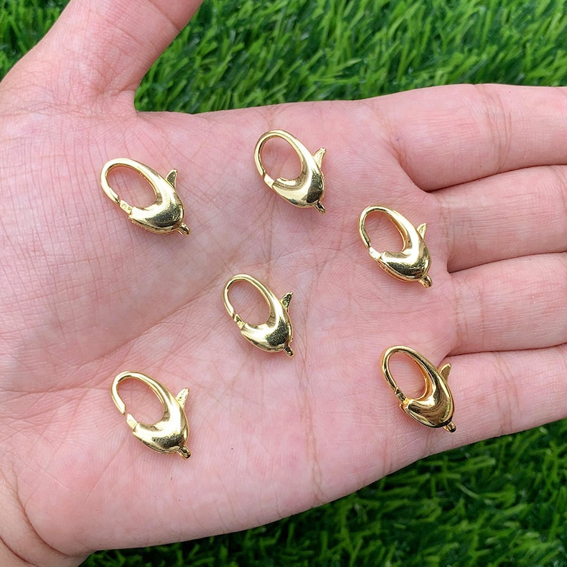 May include: Six gold-toned metal lobster clasps with a dolphin design.