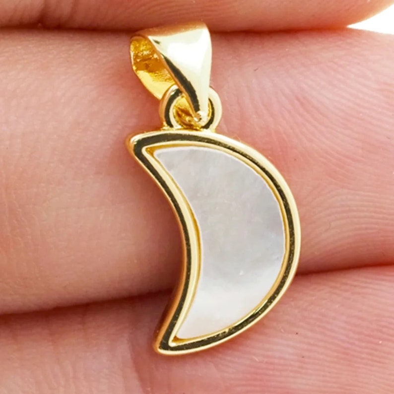 May include: Gold crescent moon pendant with a white mother of pearl inlay.