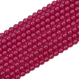 May include: A strand of round, polished beads in a vibrant, deep magenta-pink color. The beads are uniform in size and shape, arranged in multiple parallel rows, showcasing a smooth, glossy surface texture that reflects light across each sphere.