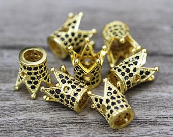 May include: A set of six gold-tone crown-shaped beads with black cubic zirconia stones. The beads are designed to be used as end caps for necklaces or bracelets.