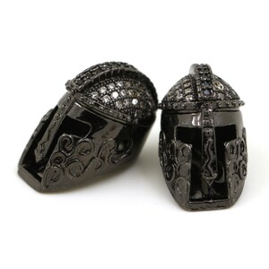 May include: Two black metal Spartan helmet charms with clear rhinestone accents.