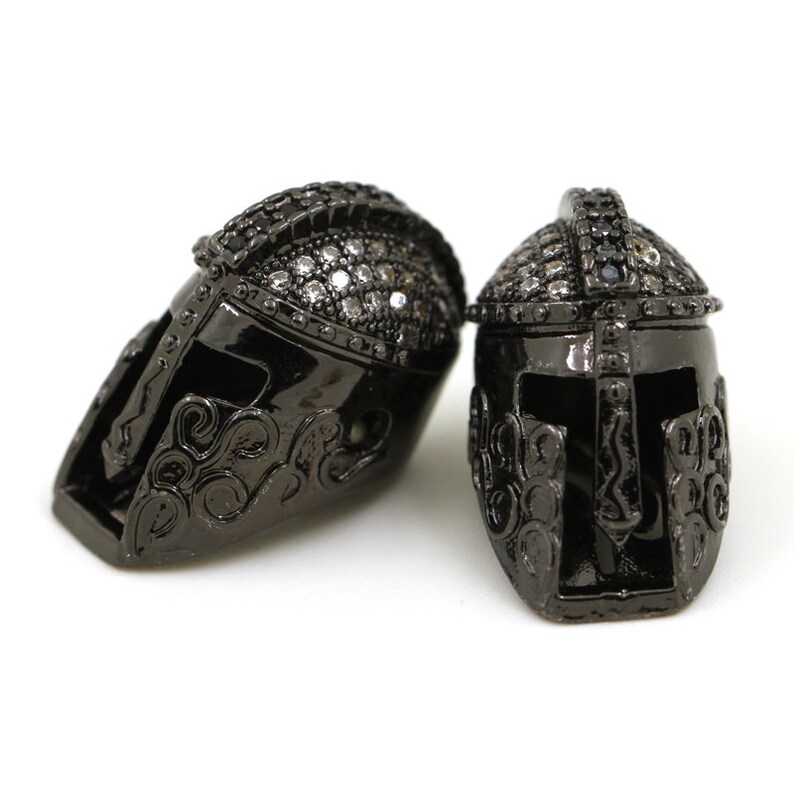 May include: Two black metal Spartan helmet charms with clear rhinestone accents.