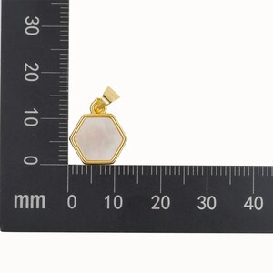 May include: A gold-toned pendant with a hexagonal white mother-of-pearl inlay. The pendant is approximately 1.5 cm wide.