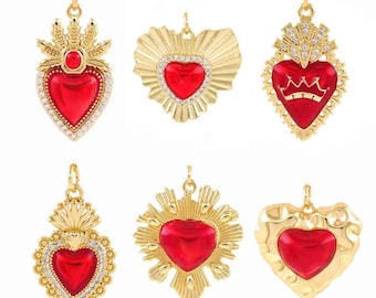 May include: Six gold-colored pendants with red heart-shaped centers. The pendants have various designs, including sunbursts, crowns, and ornate detailing with clear crystals. Each pendant has a loop for attaching to a chain or other jewelry.