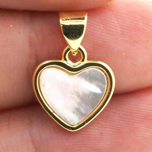 May include: A gold heart-shaped pendant with a white mother-of-pearl inlay.