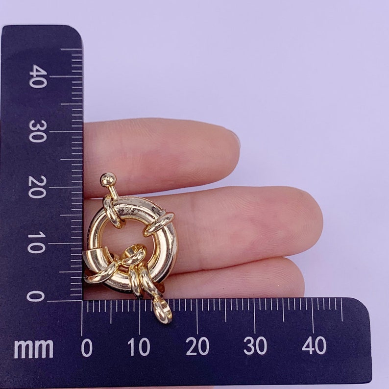 May include: Gold-toned metal ring clasp with a decorative knot design. The clasp measures approximately 2 cm in diameter.